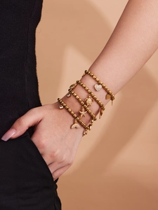 Close-up of gold layered bracelets with heart, sea turtle, and starfish charms on wrist