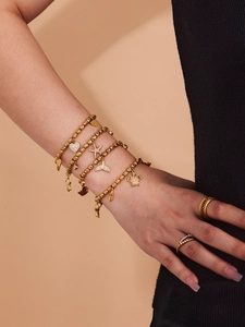 Detail of gold beaded bracelets featuring starfish, heart, and turtle charms with crystals