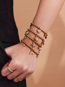 Detail of gold charms including sea turtle, starfish, and heart on beaded bracelets
