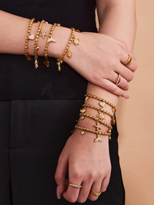 Close-up of golden beaded ocean bracelets with starfish and heart charms on model
