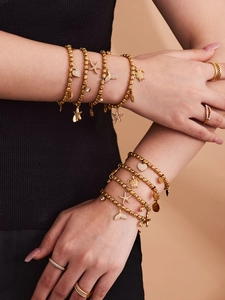 Detail of gold beaded bracelet with ocean charms like starfish and turtle on wrist