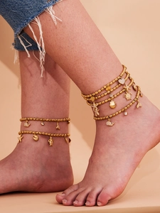 Detail of layered gold beaded anklet with sea star, turtle and heart crystal charms