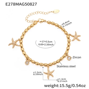 Macro detail of gold stainless steel beaded bracelet with starfish and zircon charms