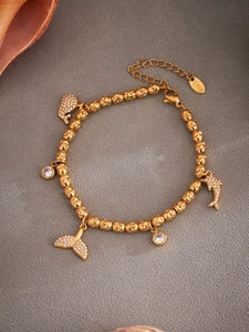 Detailed macro view of golden stainless steel beads with sparkling whale tail and dolphin charms