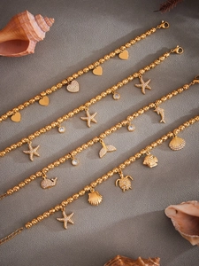 Detail of gold beaded ocean bracelets featuring starfish, dolphin, and sea turtle charms