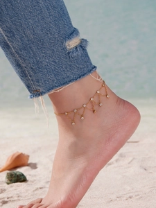Détail de la chevillère dorée à plusieurs rangs avec zircons sur la plage