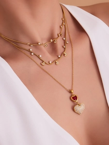 Dettaglio collana a strati in oro con ciondolo a cuore rosso e pietre in zirconia