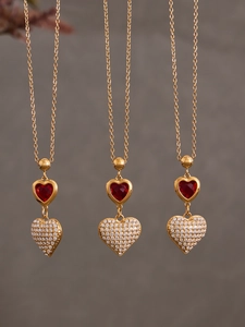 Dettaglio ravvicinato di tre ciondoli a cuore placcati oro 18k con zirconi rossi e bianchi