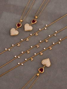 Dettaglio di ciondoli a cuore placcati in oro 18k con zirconi rossi e catene sottili