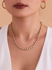 Gros plan d'un mannequin portant un collier en zircone dorée et des boucles d'oreilles torsadées