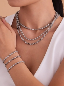 Détail de colliers et bracelets argentés avec pendentifs infini et zircone étincelante