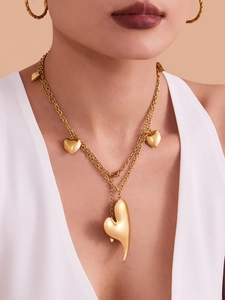 Détail d'un collier à cœur doré multicouche et de boucles d'oreilles créoles dorées