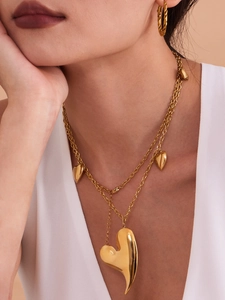 Gros plan du collier double épaisseur à cœurs dorés et boucles d'oreilles torsadées