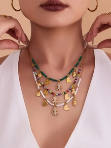 Detailed view of layered beaded octopus necklaces and gold hoop earrings on model