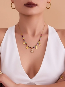 Detail of beaded necklace with gold octopus and shell pendants worn by a model
