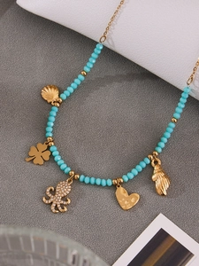 Detail of octopus and shell charms on light blue beaded stainless steel necklace