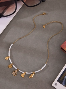 Detail of gold charms including octopus with crystals, shells, and clover on beaded necklace