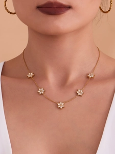 Close-up of gold chain necklace featuring five sparkling zircon flower charms on a model