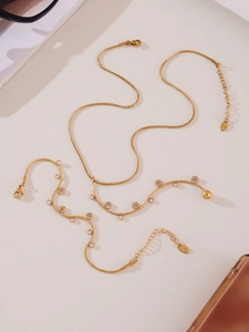 Detail of gold stainless steel necklace and bracelet set with floral charms and 5A zircons