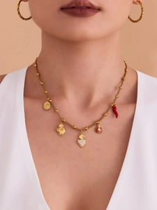 Détail d'un collier doré avec breloques cœur, pièce et piment sur mannequin avec boucles