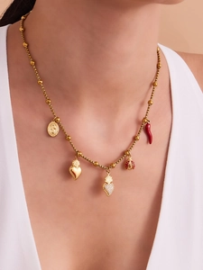 Détail d'un collier doré avec cœur, zircons, coccinelle et piment porté par un mannequin