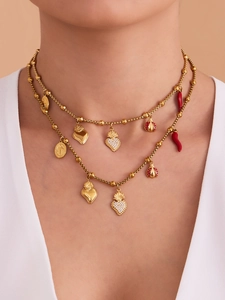 Détail d'un collier doré multicouche avec cœurs et pendentif Cornetto italien