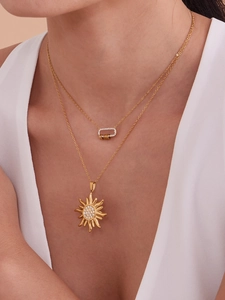Gros plan de colliers dorés superposés avec pendentifs soleil et serrure en zircon 5A