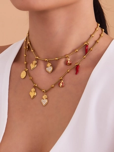 Gros plan d'un collier doré double épaisseur avec breloques cœur, piment, coccinelle et zircons