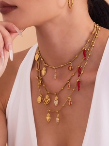 Gros plan de colliers dorés multicouches avec pendentifs cœur et piment sur un mannequin