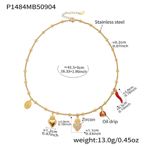 Détail des pendentifs cœur et piment rouge sur un collier de perles en acier doré