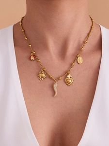 Detail of gold necklace featuring sun, heart, horn, and ladybug charms on a beaded chain