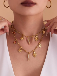 Detail of layered gold charm necklace featuring ladybug, sun, and medallion pendants
