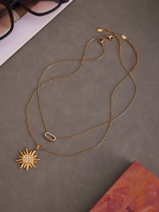 Détail d'un collier double rang doré avec pendentif soleil et pierres en zircon