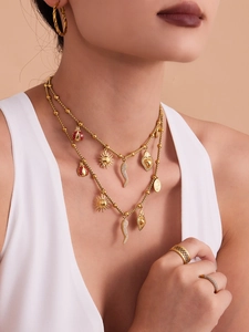 Detailed view of gold multi-layered necklace set with sun, beetle and sacred heart charms
