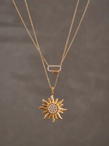 Gros plan détaillé d'un collier doré double épaisseur avec pendentif soleil et zircons 5A