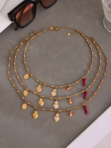 Détail des pendentifs cœur et piment rouge sur des colliers en acier inoxydable doré
