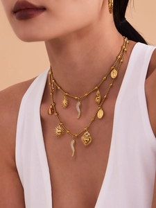 Detailed layered gold necklace with sun, heart, chili, and ladybug charms on a model