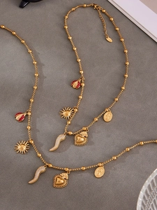 Detail of gold bead chain necklace with enamel charms and S.Steel hallmark on grey fabric