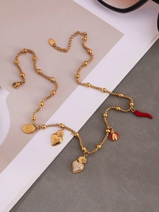 Détail du collier en acier inoxydable doré avec pendentifs cœur et breloques fantaisie