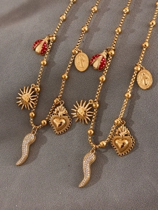 Macro view of gold-plated necklaces with ladybug, sun, heart, and chili charms