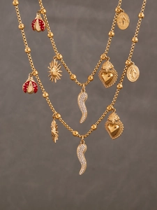 Detail of gold multi-charm necklace featuring enamel ladybug and zirconia heart pendants