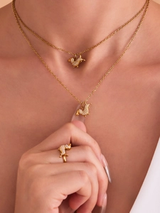 Dettaglio di modella che indossa set collana e anello a forma di cane in oro e zirconi