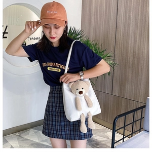Close-up of white canvas tote featuring a 3D plush bear detail and durable shoulder strap