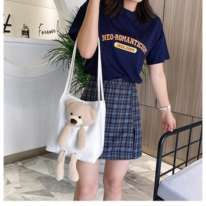 Detailed view of white canvas tote bag featuring 3D plush bear on a female model
