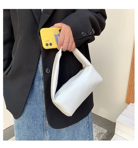 Detail of minimalist white cylinder bag with smooth faux leather and metallic top zipper