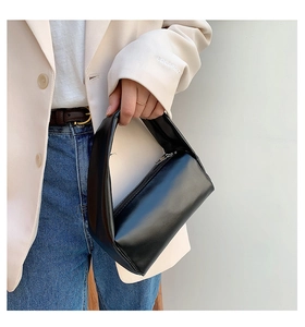 Detail of a black minimalist leather handbag showing the sleek cylindrical design and texture