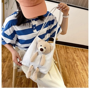 Detail of white canvas tote bag with a 3D plush teddy bear mascot on the front