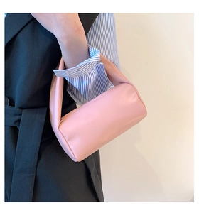 Close-up of a pink cylindrical handbag with smooth leather texture and wide top handle