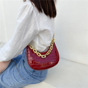 Deep red crocodile embossed crescent bag with chunky gold chain strap shown on model