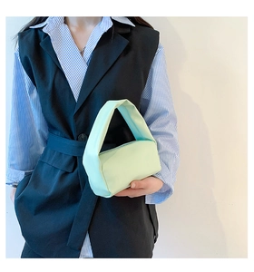 Detail of mint green minimalist cylindrical handbag featuring a unique twisted wide handle